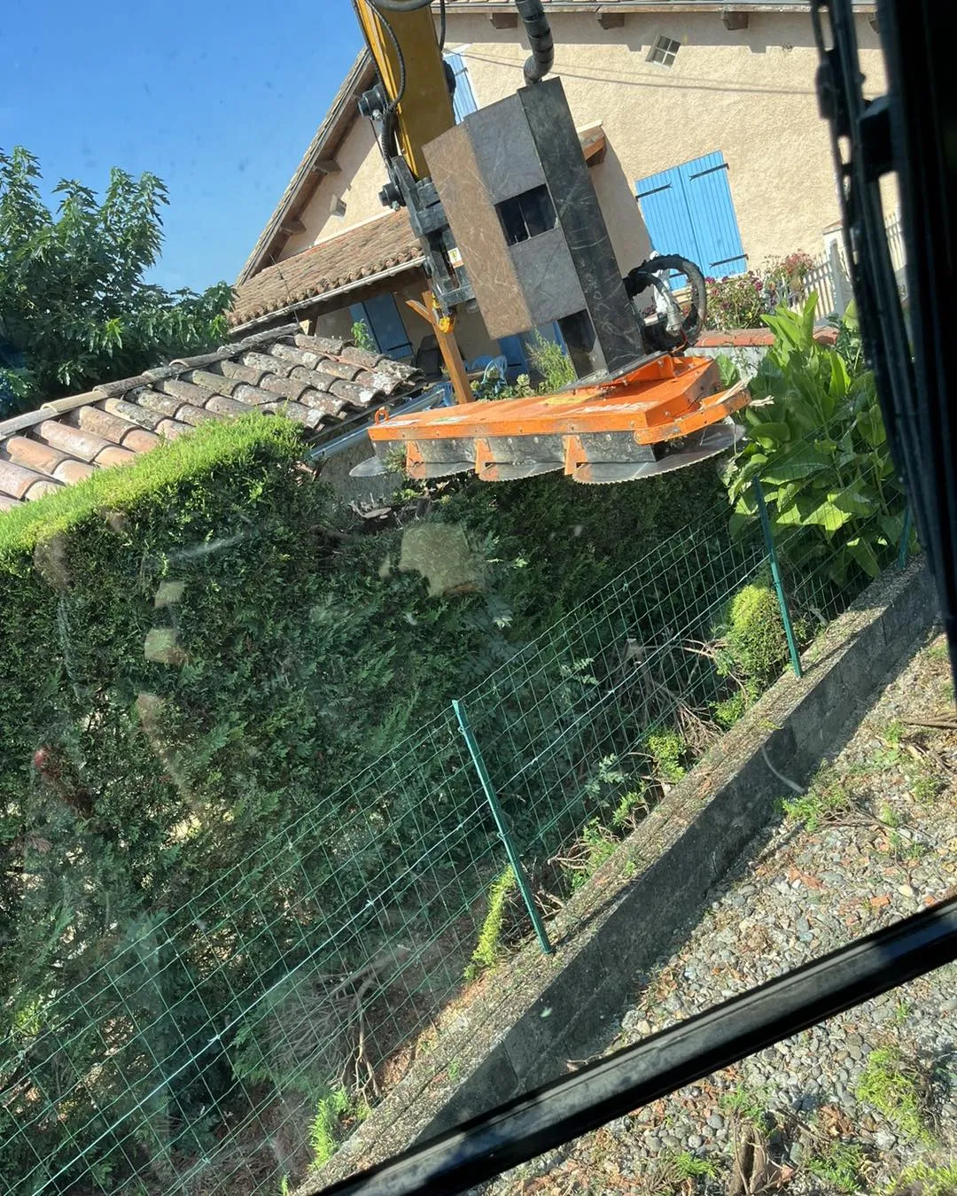 Lamier effectuant l'élagage d'une haie dans un jardin résidentiel.