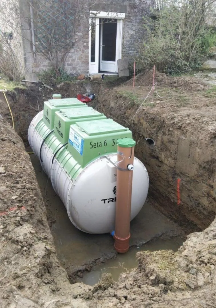 Installation d'une cuve d'assainissement dans une cour, mise en place par des professionnels.